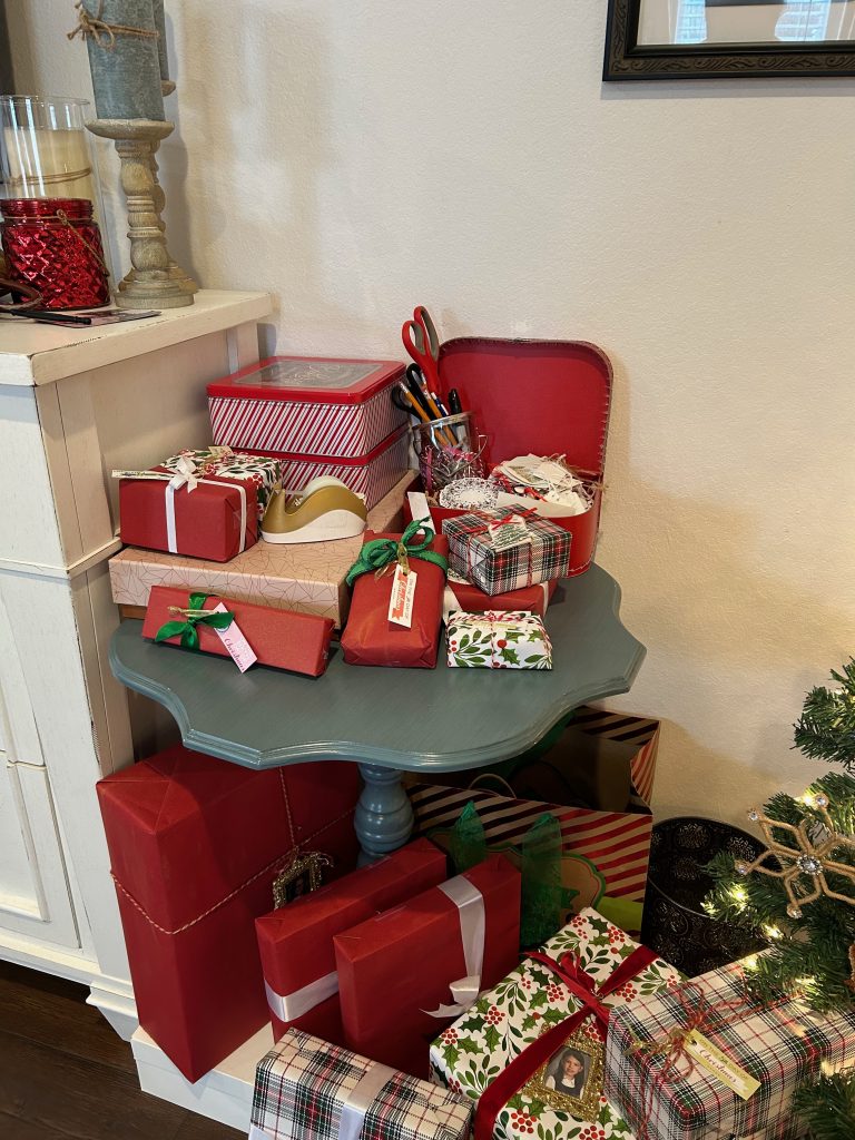 Wrapped gifts on floor and table with several wrapping supplies