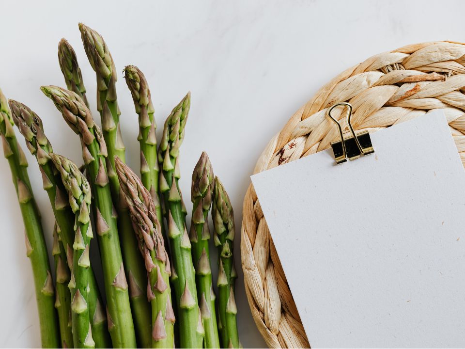 notepad for grocery list meal plan with a notepad next to asparagus for writing a grocery list