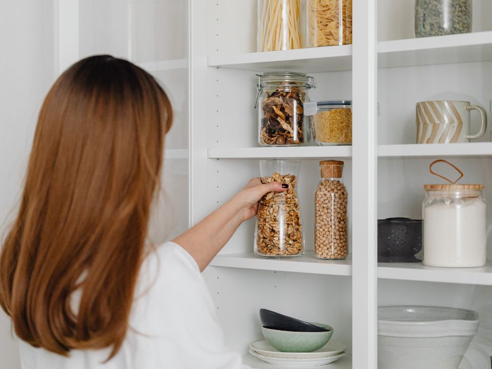 pantry inventory Woman reaching for a jar of granola in a pantry know what is in the pantry when meal planning